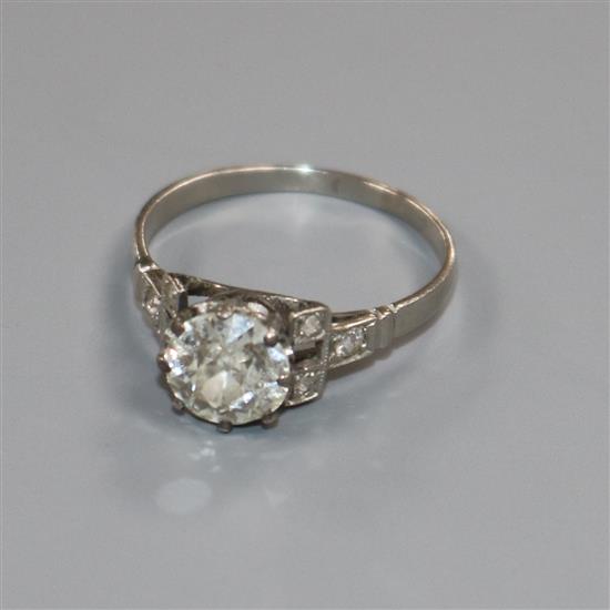 A white metal and single stone diamond ring with diamond set shoulders, size L.